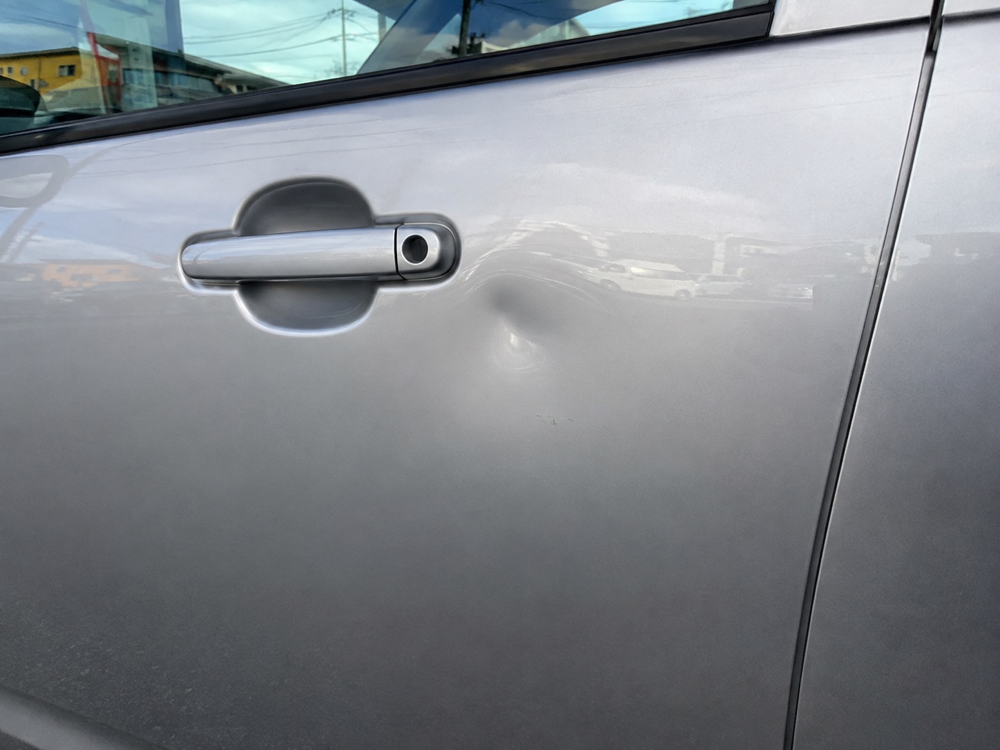 silver の車の前ドアにできた浅いへこみのクローズアップ