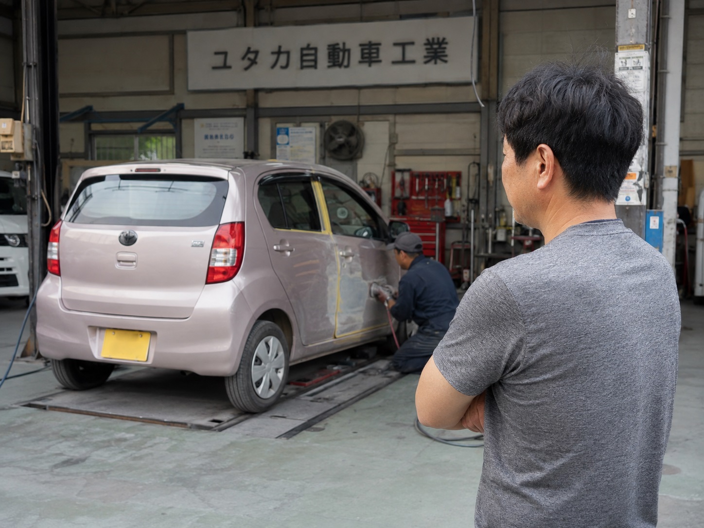 工場の前で自分の車を見ながら考え込む男性